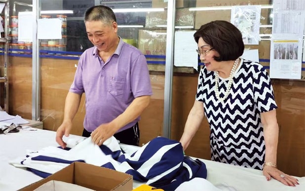 Mok Sau-jean (right), a seasoned fashion professional from Hong Kong, inspects her workshop in Zhongshan and talks with an employee.