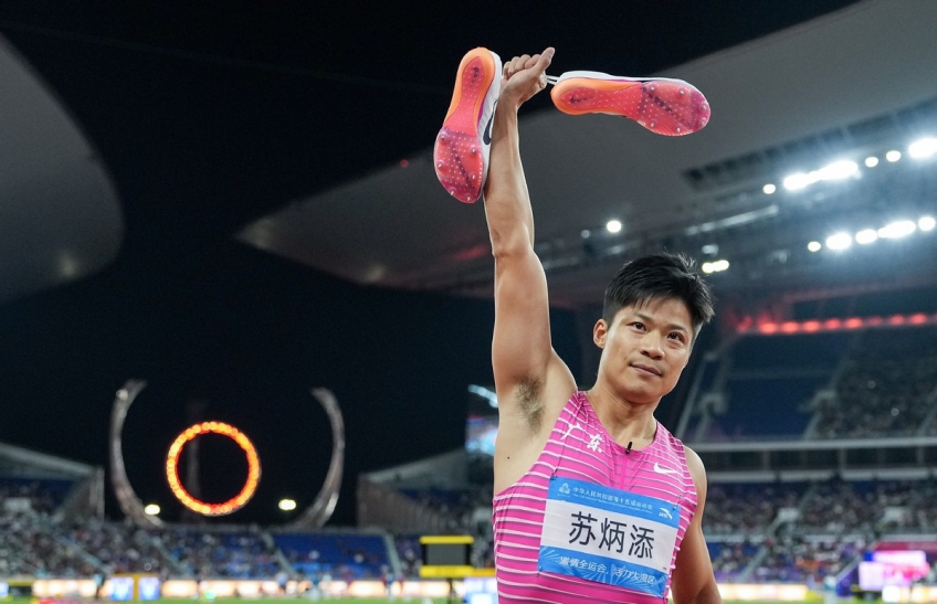 Su Bingtian acknowledges the crowd with his track shoes held in the air after competing in the men’s 4x100m relay race at the 15th National Games in Guangzhou on November 20, 2025, in a gesture signaling his retirement. [Photo/Xinhua]